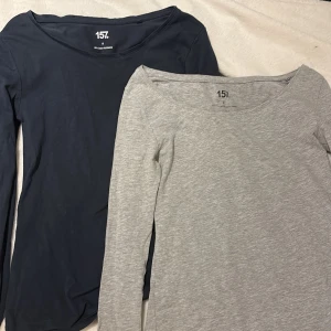 2 långärmade toppar från laget 157, st S - Två basic långärmade toppar från 157 i storlek S. En är mörkblå och en är ljusgrå, båda med rundad halsringning och figurnära passform. Den grå är i bomull, viskos och elastan, den blå i bomull och elastan. Perfekta att styla med smycken eller under en jacka. 💝