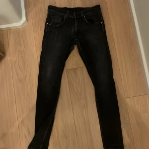 Svarta skinny jeans - Säljer ett par svarta skinny jeans med klassisk femficksdesign och snygga slitningar. Jeansen har smal passform och är perfekta för dig som gillar en tajt look. Materialet är stretchigt för extra komfort.