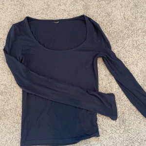 Mörkblå långärmad topp med rund hals - En mörkblå, tight långärmad topp med rundad, djup urringning. Toppen har en slits längst ut i ärmen och har en enkel, stilren design som passar perfekt till jeans eller kjol. Mjuk och stretchig i materialet för en bekväm passform. Har tyvärr klippt bort lappen i tröjan så ser inte storleken, men skulle gissa på XS/S!!❣️❣️