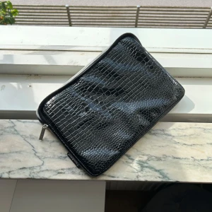 Svart kuvertväska i skinnimitation - Säljer detta datorfodral då det var för litet för min dator. Storleken är ca 34x23 Extremt fint material i ormskinn och vadderad insida med mjukt tyg. helt oanvänt!❤️