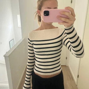 Randig ribbad lite offshoulder topp H&M strl S - Säljer en snygg ribbad med lite offshoulder topp från H&M i vitt/beige och svart. Toppen är croppad med långa ärmar och har ett klassiskt randigt mönster. Perfekt för dig som gillar en stilren men trendig look. Super skön och fin basic tröja 💗strl S men passar även Xs