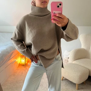 Beige stickad polotröja från H&M - Oversized beige stickad polotröja från H&M med ribbade muddar och hög krage. Tröjan har lång ärm, slits i sidorna och en loose fit som ger en chill vibe. Perfekt för lager-på-lager under kyliga dagar.