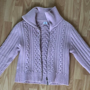 Ljusrosa stickad kofta Boomerang - Superfin ljusrosa stickad kofta från Boomerang i storlek M. Koftan har kabelstickat mönster, hög krage och dragkedja framtill. Är gjord i ull.