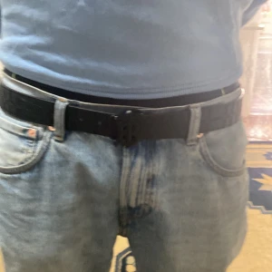 Burberry bälte - Säljer ett svart skärp från Burberry med rutigt mönster och ett stilrent B-format metallspänne. Skärpet är gjort i skinn och har en snygg, klassisk design som passar till jeans eller kostymbyxor. Perfekt accessoar för att lyfta din outfit.