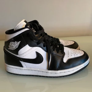 Nike Air Jordan 1 svartvita sneakers - Säljer ett par Nike Air Jordan 1 sneakers i svart och vitt skinn i väldigt bra skick. Klassisk high-top modell med svart swoosh, perforerad tå och ikoniska Air Jordan-loggan på sidan. .