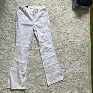 Vita bootcut byxor från Mexx - Snygga vita bootcut-byxor från Mexx med klassisk passform och hällor för bälte. Byxorna är tillverkade i bomullsmix med lite stretch för extra komfort. Perfekta för dig som gillar stilrena och fräscha looks.