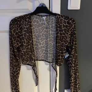 Leopardmönstrad bolerotopp NLY Trend XS - Snygg bolerotopp från NLY Trend i transparent mesh med leopardmönster. Toppen har långa ärmar, croppad passform och knyt framtill. Perfekt för att lyfta vilken outfit som helst med lite extra edge.