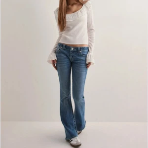 True Religion bootcut jeans blå, stl 26 - Snygga blå jeans från True Religion med klassiska kontrastsömmar och ikoniska bakfickor. Modellen har bootcut-ben och låg midja, tillverkade i mjukt jeanstyg. Perfekta för dig som gillar en tidlös och avslappnad look.
