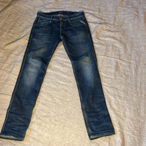 Blå Replay jeans straight fit - Säljer ett par snygga blå jeans från Replay med klassisk femficksdesign och raka ben. Jeansen har en mörk tvätt med lätt slitning och tydliga kontrastsömmar. Bakfickan har Replay-logga och läderpatch i midjan. Perfekta till sneakers eller boots. 1600 nypris mitt pris 499. Kan gå ner i pris vid snabb affär