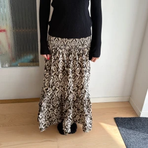 Mönstrad långkjol från Zara - Supersnygg långkjol från Zara i beige och svart med unikt mönster. Kjolen har smock i midjan för en bekväm passform. 