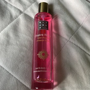 Rituals Chakra Water Body Mist 50ml - Rituals Chakra Water bed & body mist med doft av indisk ros och Himalaya-honung. Flaskan är cylinderformad i transparent rosa plast med gulddetaljer och dekorativt mönster. Rymmer 50 ml och har en lyxig känsla med guldlock.