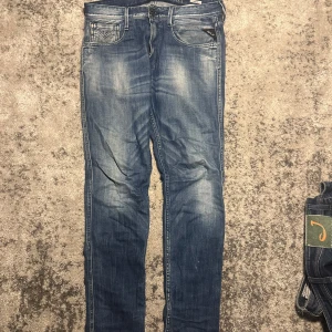Replay blå jeansbyxor slim fit - Snyggare blå jeansbyxor från Replay med klassisk femficksdesign och diskreta slitningar framtill. Jeansen har smal passform och raka ben, med detaljerade sömmar och läderpatch bak i midjan. Perfekta för en avslappnad och trendig look.