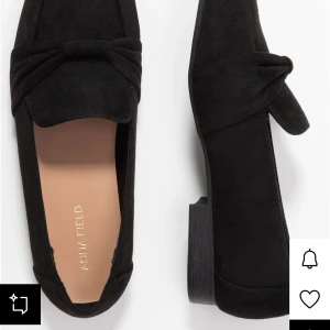Svarta mockaloafers från Anna Field - Stilrena svarta loafers i mocka från Anna Field med låg klack och dekorativ knut framtill. Skorna har en klassisk rund tå och platt sula, perfekta för en clean och trendig look. Helt nya fortfarande i deras paket