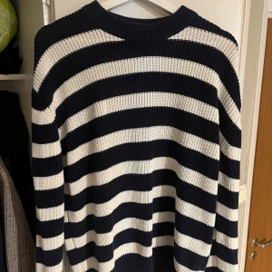 Randig stickad tröja Octobre editions - Säljer en snygg randig tröja från Octobre Editions i marinblått och vitt. Tröjan är stickad i 100% bomull, har rund hals och långa ärmar. Perfekt för dig som gillar klassisk stil med en modern twist.