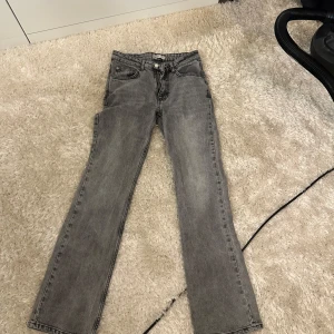 Grå raka jeans - Snygga grå jeans med rak passform och klassisk femficksdesign. Jeansen har en enkel look med knapp och dragkedja framtill. Perfekta till sneakers eller boots för en chill vibe.