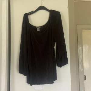 Svart plisserad blus från Lindex XL - Säljer en svart plisserad blus från Lindex i storlek XL. Blusen har en snygg vid urringning och långa, luftiga ärmar med resår vid handlederna. Materialet är lätt och har en diskret glansig känsla som ger extra stilpoäng.