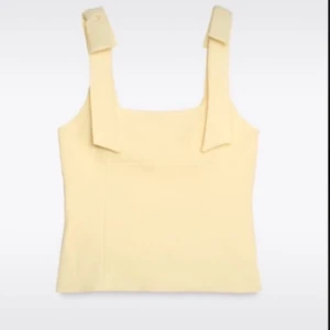  Populär slutsåld zara topp med prislapp - Snygg ljusgul linnetopp med breda axelband som knyts upptill. Toppen har en rak och enkel passform och är perfekt för varma dagar. Stilren och trendig design som passar till många olika outfits.