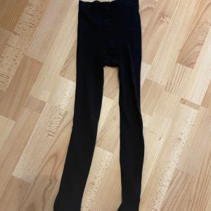 Svarta strumpbyxor från Lindex - Svarta strumpbyxor från Lindex i stretchigt material. Perfekta att bära till vardags eller under en klänning. Bekväm passform och elastisk midja. Passar barn i storlek 146/152. ALLA PLAGG TVÄTTAS INNAN DEM BLI SKICKADE!!