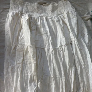 Vit långkjol med volanger från bikbok - Från bikbok. Har en slit på sidan av benet.