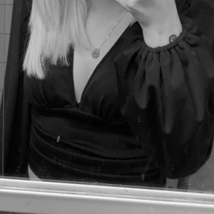 Svart omlottopp med puffärmar - Snygg svart omlottopp med djup v-ringning och långa puffärmar. Toppen har en figurnära passform och markerad midja, perfekt för att lyfta din outfit.