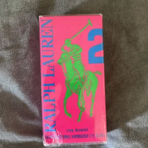 Ralph Lauren Big Pony 2 Eau de Toilette för kvinnor - En färgstark parfym för kvinnor från Ralph Lauren, Big Pony 2. Flaskan är rosa med en grön polospelare och blå siffra 2 på framsidan. Innehåller 50 ml Eau de Toilette Spray.