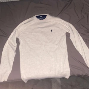 Ljusgrå tröja från Polo Ralph Lauren - Säljer en stilren ljusgrå tröja från Polo Ralph Lauren med den klassiska broderade loggan på bröstet. Tröjan har rund halsringning och långa ärmar. Perfekt för en enkel och snygg look. Aldrig använd, bara testat på.