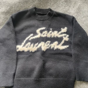 Svart stickad tröja från Saint Laurent - Säljer en svart stickad tröja från Saint Laurent med vit, fluffig logotyp framtill. Har inte använt och storlek L. Har inte kvitto och prislappen är inte kvar. Skriv till mig om du undrar.