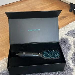 Artist Pro Heated Brush & Straight - En svart och blå elektrisk värmeborste från OBH Nordica Artist Pro. Borsten är designad för att både borsta och platta håret, med jonfunktion och keramisk beläggning. .