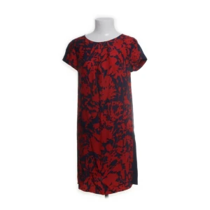 Blommig sidenklänning fr. Max&Co - Säljer en elegant kortklänning fr. Max&Co i 100% siden med rött blommönster på marinblå botten. Klänningen har korta ärmar och en rak passform. Perfekt för dig som vill sticka ut med ett färgstarkt mönster.