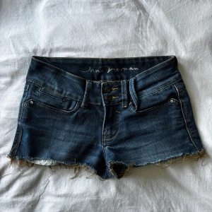 lågmidjade jeansshorts från Jane Norman - jätte snygga mörkblå jeansshorts från Jane Norman med låg midja, råa fransiga kanter och dubbla knappar framtill. snygga bakfickor och mkt bra skick. storlek s-m💘