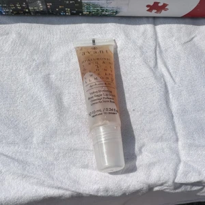 Avani Hyaluronic Argan Oil Sweet Almond Lip Scrub - Läppscrub från Avani med hyaluronsyra, arganolja och sötmandel. Kommer i en genomskinlig tub med skruvkork och applikator. Perfekt för att återfukta och vårda läpparna med en lätt och fräsch känsla.