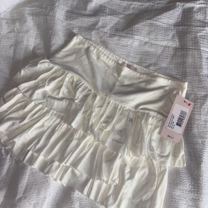 Vit volangkjol från Nelly - Supersöt vit kjol med två lager volanger från Nelly. Kjolen har en kort modell och bred resår i midjan för en bekväm passform. Perfekt att styla med en enkel topp för en trendig look. Nu med pris lapp kvar