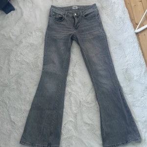 Grå bootcut jeansbyxor - Säljer ett par grå jeansbyxor i bootcut-modell lågmidjade , storlek S och längd short. Klassisk femficksdesign och normal passform. Säljes pågrund av att dom är för stora