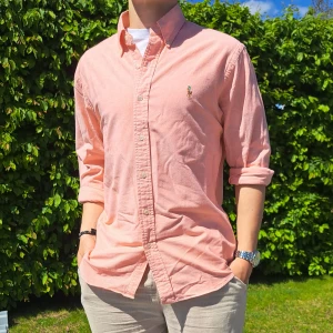 Aprikos Ralph Lauren skjorta - Stl M, Slim fit - Hej säljer en snygg Ralph Lauren skjorta I färgen aprikos. Perfekt till sommaren! 🏝🏖 Skick: 9/10 utan defekter. Stl: L, i lappen, Slim fit. Men passar bättre en M. Han på bilden är 170cm. 🤗