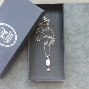 Halsband med vinglas-hänge.🍷 - Snyggt silverfärgat halsband  med ett hänge format som ett vinglas. Framsidan av glaset är dekorerad med små glittrande stenar för extra bling. Perfekt accessoar för dig som gillar unika smycken!