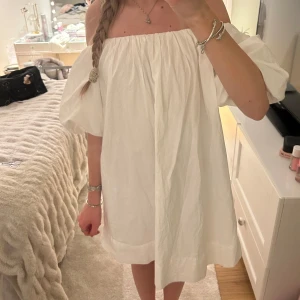 Vit offshoulder klänning från Gina Tricot - Säljer en vit offshoulder klänning från Gina Tricot i storlek S. Klänningen har puffiga korta ärmar och en lös passform. Perfekt för varma dagar och enkel att styla med smycken eller sandaler.