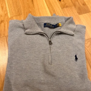 Grå tröja med dragkedja från Polo Ralph Lauren - Säljer en stilren grå tröja från Polo Ralph Lauren med dragkedja och klassisk krage. Tröjan har långa ärmar och en broderad logotyp på bröstet. Perfekt för en avslappnad men ändå elegant look. Perfekt nu inför sommaren tröjan är använd endast ett fåtal gånger. Den är som ny. Ny pris är 2 400 kr. Pris kan diskuteras 