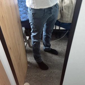 Blå jeans från Replay - Säljer ett par snygga blå jeans från Replay Hyperflex. De har modellen anbass passform med klassisk femficksdesign och knappgylf. Perfekta för en avslappnad stil.