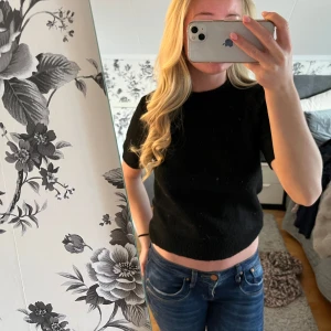 Svart tre kvarts tröja - Säljer en svart croppad stickad tröja med korta ärmar och rund hals. Tröjan har en mjuk känsla och är lätt att matcha med olika outfits.