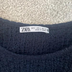 Svart ribbad t-shirt från Zara - Säljer en svart ribbad t-shirt från Zara i storlek S. Den har en enkel design med korta ärmar och rund halsringning. 