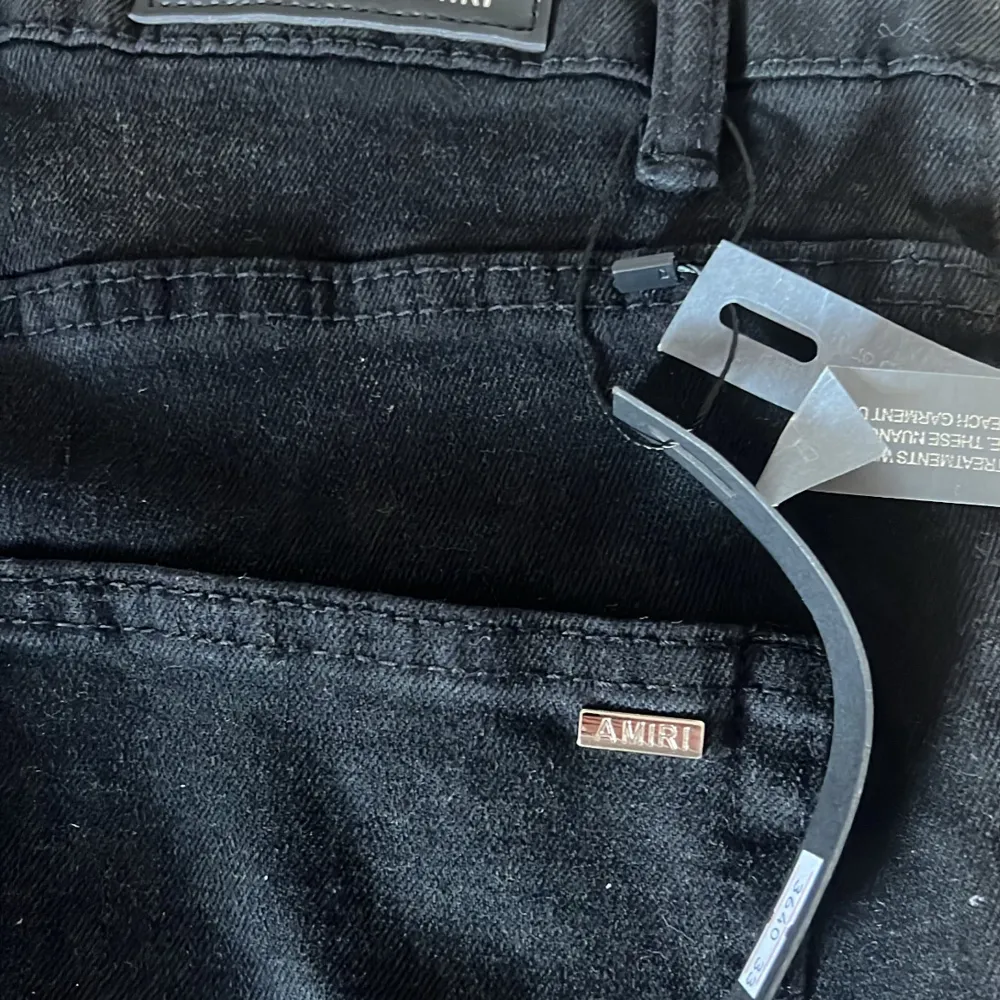 Snygga svarta jeansbyxor från Amiri med slitna detaljer och broderade bokstäver. Perfekta för en trendig look med en tight passform.. Farkut & Housut.