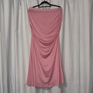 Rosa långkjol med rynkade detaljer - Säljer en rosa långkjol med snygga rynkade detaljer längst sidorna. Kjolen är gjord i ett mjukt, stretchigt material som sitter skönt mot kroppen. Perfekt för dig som gillar en feminin och stilren look.