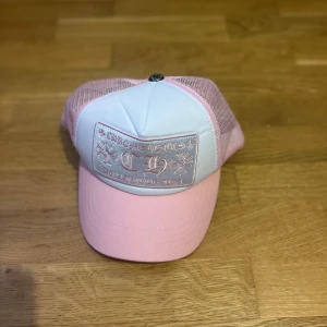 Chrome Hearts rosa vit keps - Säljer en Rosa Vit keps från Chrome Hearts som jag fick av mina föräldrar. Jag säljer pga att kepsen är inte min stil men den är fortfarande riktigt snygg för ni som gillar streetwear och drip stilen. Den är äkta vilket kan ses från bilderna.