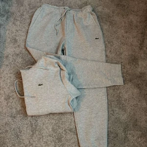 Grå hoodie och mjukisbyxor från Lacoste - Tjena, säljer en tracksuit från lacoste. Båda plaggen är nästintill helt nya då det är lite för stort för mig säljer jag. Storleken är S men passar även M. Hör av er vid fler funderingar eller fler bilder på plaggen!