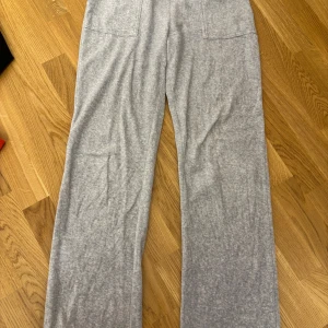 Grå mjukisbyxor från Juicy Couture - Säljer ett par grå mjukisbyxor från Juicy Couture med raka ben och broderad JC-logga på benet. Byxorna har fickor både fram och bak och är tillverkade i mjukt material som är skönt att ha på sig.