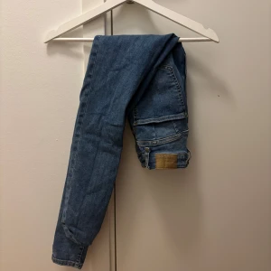 Blå skinny jeans med hög midja - Säljer ett par klassiska blå skinny jeans med hög midja. Jeansen har fem fickor, gylf med dragkedja och knapp samt en läderpatch bak i midjan. Perfekta för en stilren och enkel look.