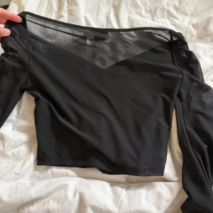 Svart mesh topp från NA-KD - Säljer en svart mesh topp från NA-KD i storlek XS. Toppen har lång ärm, croppad passform och lätt rynkdetalj framtill. 