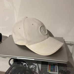 Vit keps från Stone Island - Snygg vit keps från Stone Island, minns att jag köpt den ifrån Farfetch för 1k ungefär. passform kan ställas in med spännet i bak. Väldigt snygg och minimalistisk 