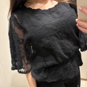 Svart spetsblus med vida ärmar - Säljer en svart blus med vackra spetsdetaljer och vida, halvtransparenta ärmar. Blusen har rund halsringning och ett elegant mönster i spetsen. Perfekt för dig som vill ha en feminin och stilren topp.🙌🏼🫶🏼