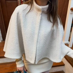 Poncho  - Säljer en stilren vit capejacka med hög krage och vid passforme. Jackan har en elegant och minimalistisk look, perfekt för att lyfta vilken outfit som helst. Materialet är mjukt och ger en lyxig känsla. PRIS KAN DISKUTERAS!!
